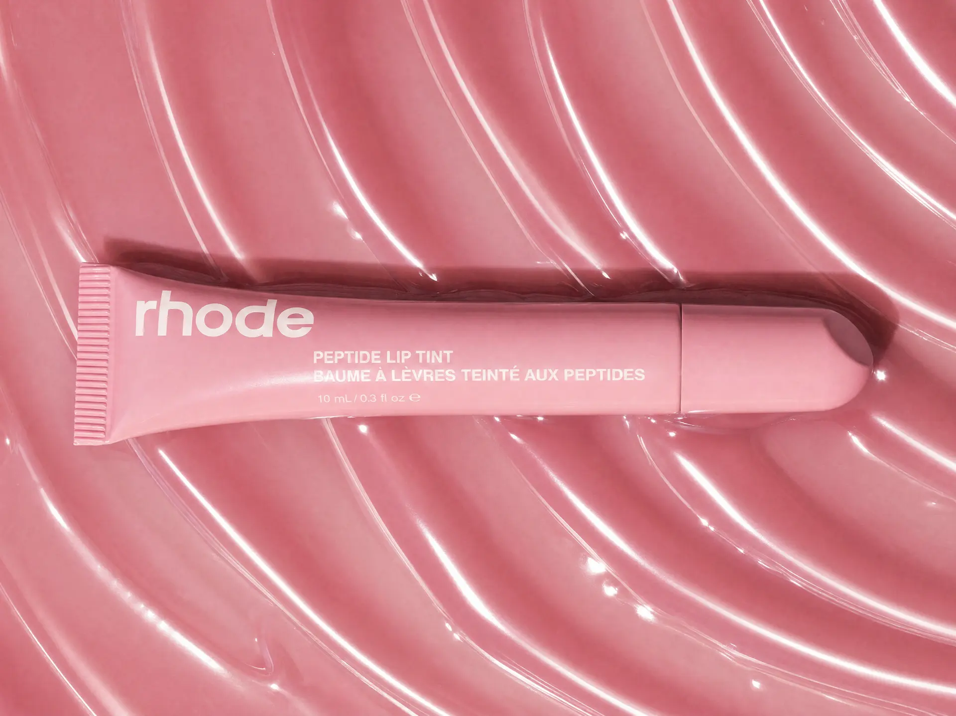 Rhode peptide lip tint on glossy pink texture